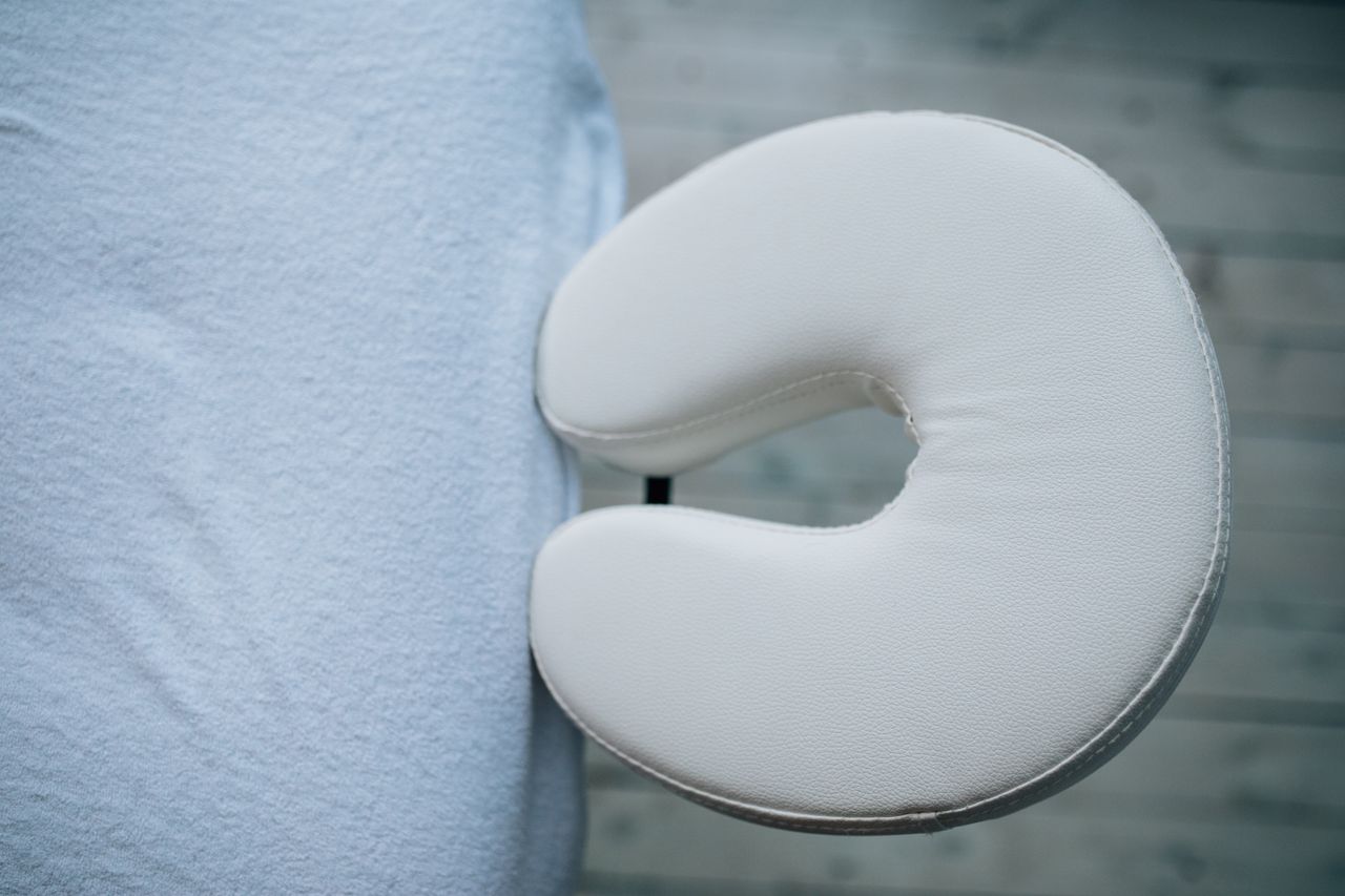 About Minimalistic top view of a massage table with a white headrest cushion for relaxation.