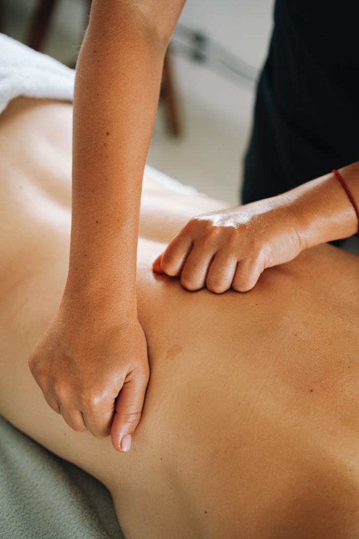 Services Close-up of a relaxing therapeutic massage focusing on back muscles in a tranquil spa environment.